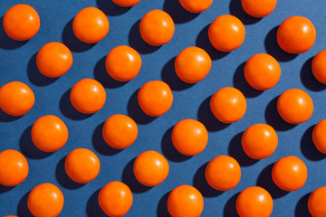 Orange round chocolate candies on a blue background with a tight shadow