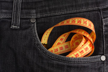 Measure tape lies in black jeans.