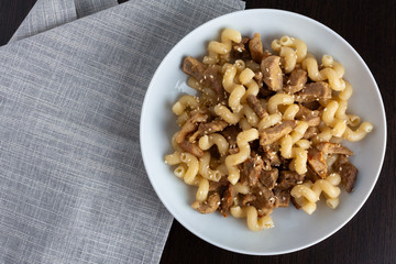 Pasta with meat and sesame in a plate next to it is a napkin.