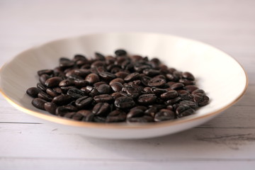 Coffee beans are in a white porcelain saucer