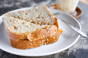slice of bread with sunflower seeds and milk for breakfast on the white plate and fork