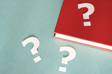 three question marks cut out of paper, one of them on the red book