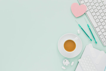 Coffee cup and heart with copy-space on medical desk flat lay pastel green