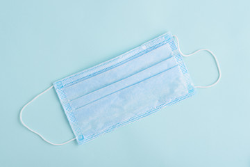 one disposable medical mask on blue background