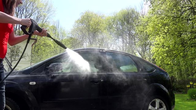 woman clean spray black car with water washer outdoor 4K