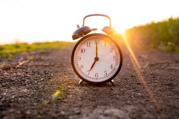 Old alarm clock at sunset shows seven o'clock