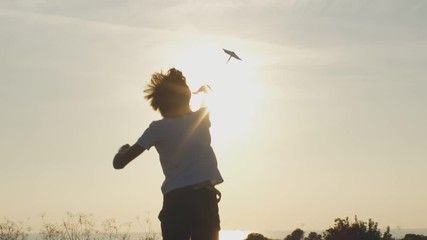 Back view of kid playing with paper plane in park