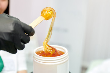 wrapping sugar paste for sugaring from a white jar on a wooden spatula