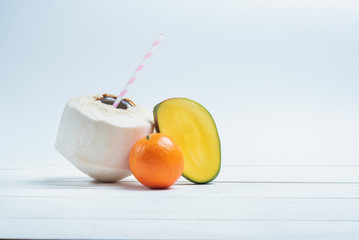 Drinks coconut with straw, half of mango and mandarin.