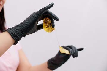 a ball of sugar paste in the hands of black gloves. preparing for the sugaring procedure