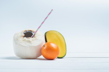 Drinks coconut with straw, half of mango and mandarin.