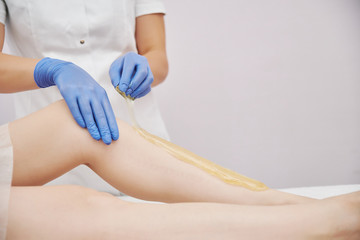 Fototapeta premium the procedure shugaring. master in blue medical gloves apply sugar paste with his hands