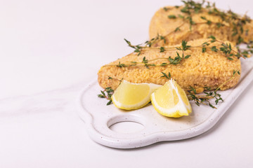 Raw ready to cook chicken breast fillets with breading, lemon, thyme
