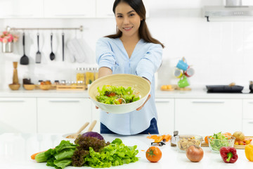 Young Woman Cooking in the kitchen. Healthy Food - Vegetable Salad Diet. Healthy Lifestyle. Cooking delicious food during the COVID-19 self-quarantine 14 days. Stay at home concept.