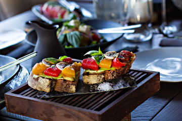 avocado toast with bell pepper served on a wooden plank.