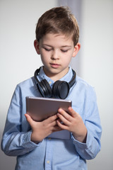 a lovely young pupil looking at his tablet wearing headphones