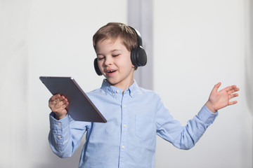 technology - a lovely young pupil rejoicing and jumping with his tablet wearing headphones and smiling