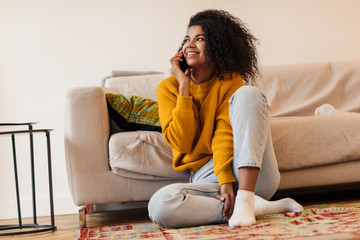 Image of african american woman talking on cellphone while sitting