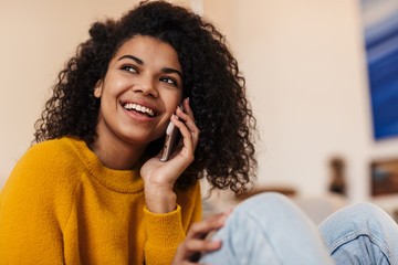 Image of african american woman talking on cellphone while sitting