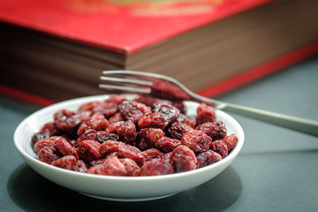 Closeup view of a White plate Full of Dried Cranberries and vintage book