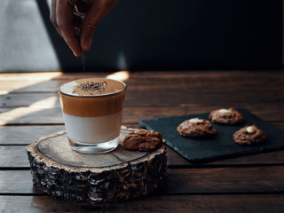 Homemade creamy dalgona coffee along with some homemade cookies. Hand sprinkling chocolate on top. Dark photography