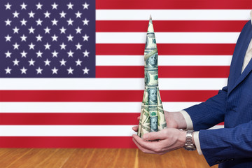 Rocket of money in the hands of a businessman on the background of the American flag.