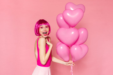 Obraz na płótnie Canvas Image of excited nice woman in wig holding balloons and smiling