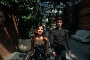 beautiful couple-a girl in a magnificent dress and a guy in a black shirt and trousers are in a building with a beautiful interior