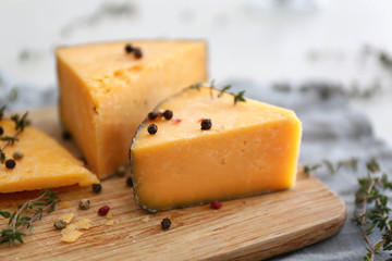 Tasty cheese with thyme and spices on wooden board, closeup