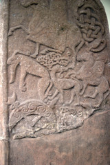 Ancient abstract design carved onto a standing stone in northern europe.  Shows animals and riders on horses possibly hunting.