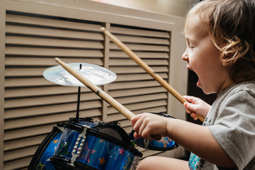 Fototapeta premium A little boy 2 years old plays drums with sticks
