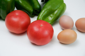 Tomato bell peppers and eggs on a white table