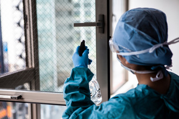 窓のウイルス除菌をする作業員