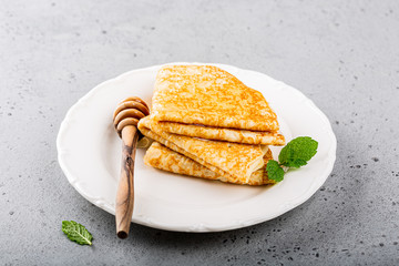 Delicious Tasty Homemade crepes or pancakes with honey, honey and mint on white plate. Healthy breakfast concept, gluten free.