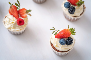 Fresh, delicious cupcakes with yogurt cream and fresh berries. Close up