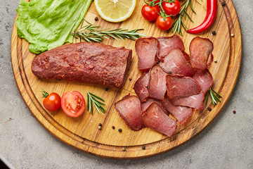 Armenian basturma or Pastirma on wooden cutting board decorated with spices, lettuce, lemon and tomatoes. Meat smoked jerky good as Beer snack