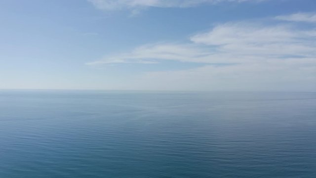 An aerial 4K video view of eternal blue sea or ocean with sunny and cloudy sky.