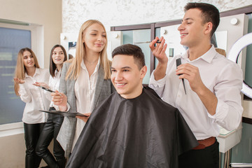 Young man with professional hairdresser and model during courses in salon