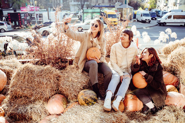 Beautiful girls sitting on haystacks take a selfie