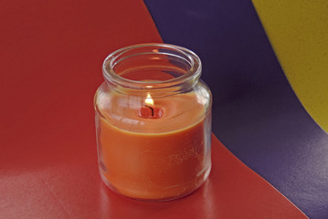 a fragrant pink candle in a decorative jar flickers with its fire.