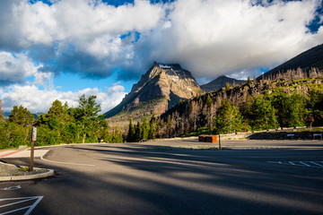An empty parking lot in the Glacier National Park, with heavy clouds touching the mountain peak in...