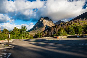 An empty parking lot in the Glacier National Park, with heavy clouds touching the mountain peak in a dramatic early morning light © mike