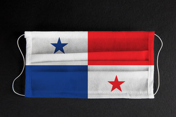 Coronavirus covid pandemic in Panama. Flag of Republic of Panama printed on medical mask on black background. National healthcare system concept. Covid-19 outbreak, spread of corona virus in America