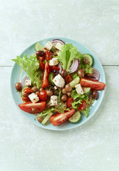 Healthy Salad with Tomatoes, Cucumber, Lettuce and Olives on bright wooden Background. Healthy Snack Idea. Top view. 