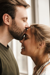 Photo of romantic cute couple smiling and kissing while standing