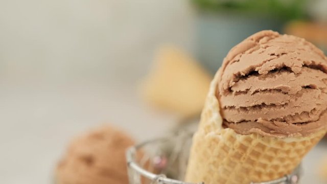 Delicious summer dessert coffee ice cream in waffle cone. Summertime healthy food concept, lactose free. Camera slide right