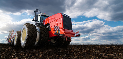 Red tractor with plow on a agricultural field © scharfsinn86