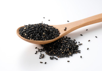 Black sesame seeds in a wooden spoon placed on a white background