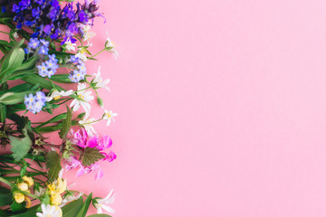 Floral flat lay of colorful spring wildflowers on pink paper background, space for text. Floral...