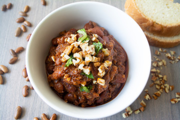 Traditional Georgian vegan kidney beam stew lobio with chopped walnuts and parsley served in a bowl with slices of bread